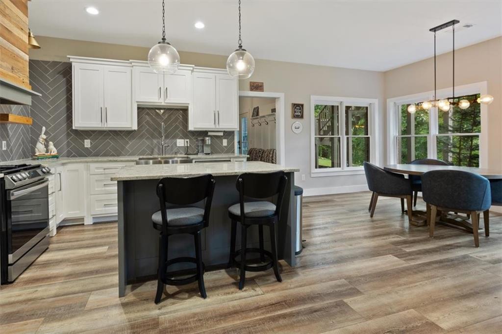 134 Prospector Ridge Dahlonega, GA 30533 - Photo 64 of 96 a large kitchen with granite countertop a stove a sink a dining table and chairs with wooden floor