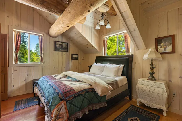 a bedroom with a bed a mirror on dresser and a window