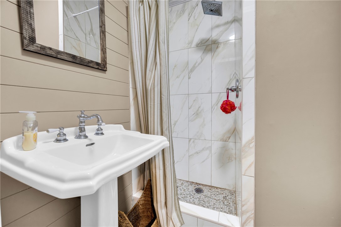 3030 Smith McGee Road Iva, SC 29655 - Photo 35 of 46 A well-appointed bath features a classic pedestal sink and a walk-in shower with natural stone tile accents.