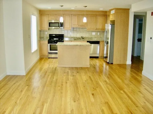 a large kitchen with stainless steel appliances granite countertop a refrigerator a stove top oven and a sink