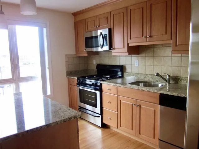 a kitchen with stainless steel appliances granite countertop a stove a sink and a microwave