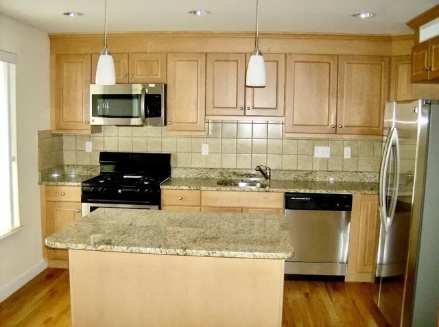 a kitchen with stainless steel appliances granite countertop a sink a stove and a refrigerator