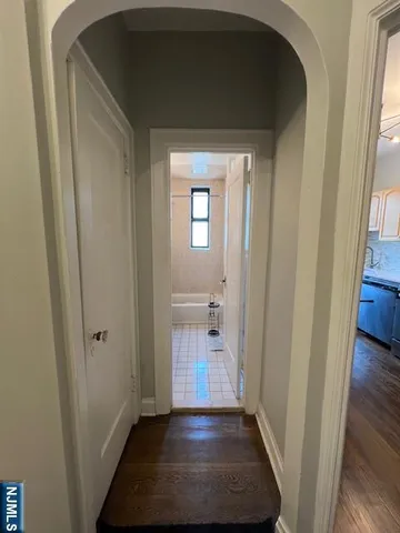a view of a hallway with wooden floor and a bathroom
