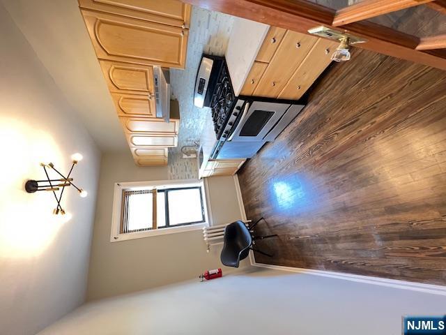 303 Hamilton Place, Unit D4 Hackensack, NJ 07601 - Photo 6 of 9 a kitchen with granite countertop a stove a chimney wooden floor and cabinets