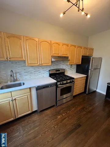 a kitchen with stainless steel appliances a sink cabinets and wooden floor