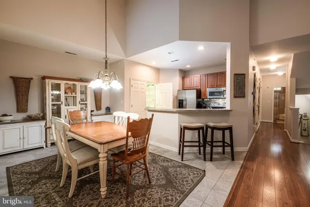 a dining room with stainless steel appliances kitchen island granite countertop a table chairs and a refrigerator