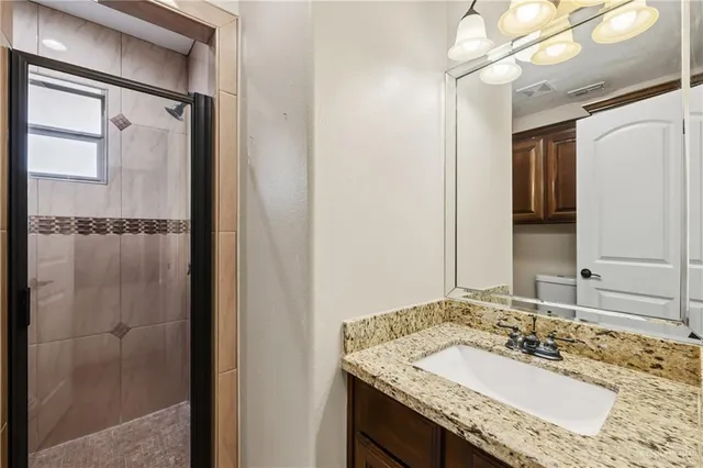 a bathroom with a granite countertop shower sink and mirror