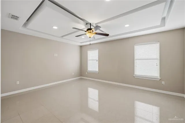an empty room with windows and ceiling fan