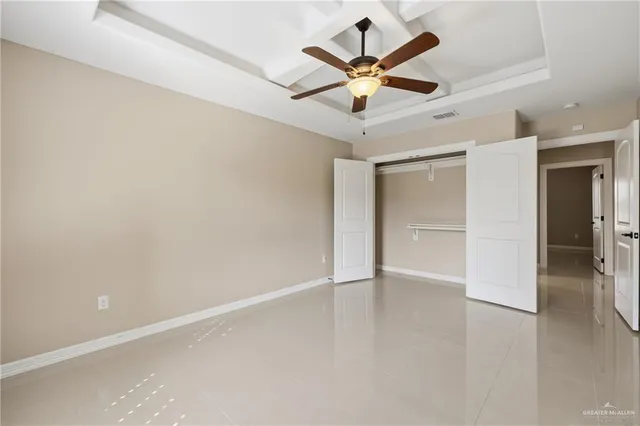 an empty room with a hallway and a ceiling fan