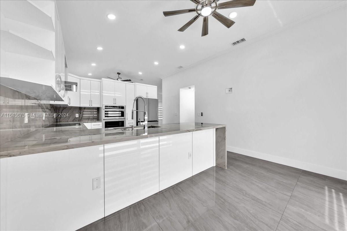 2373 Southwest 177th Terrace Miramar, FL 33029 - Photo 48 of 79 a large white kitchen with a sink and dishwasher a stove top oven with wooden floor