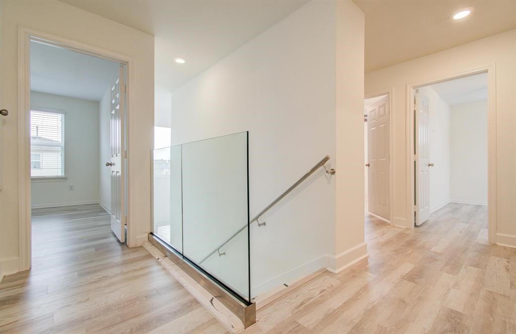 4627 Prairie Chase Drive Houston, TX 77069 - Photo 10 of 23 Luxurious upstairs landing with sleek glass railing, modern lighting, and a bright, open feel.