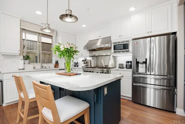 a kitchen with stainless steel appliances kitchen island granite countertop a table chairs stove and refrigerator