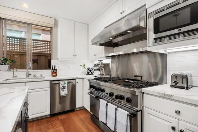 a kitchen with stainless steel appliances a sink a stove and cabinets