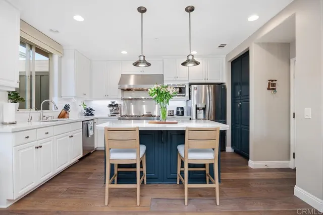 a kitchen with stainless steel appliances a dining table chairs refrigerator and sink