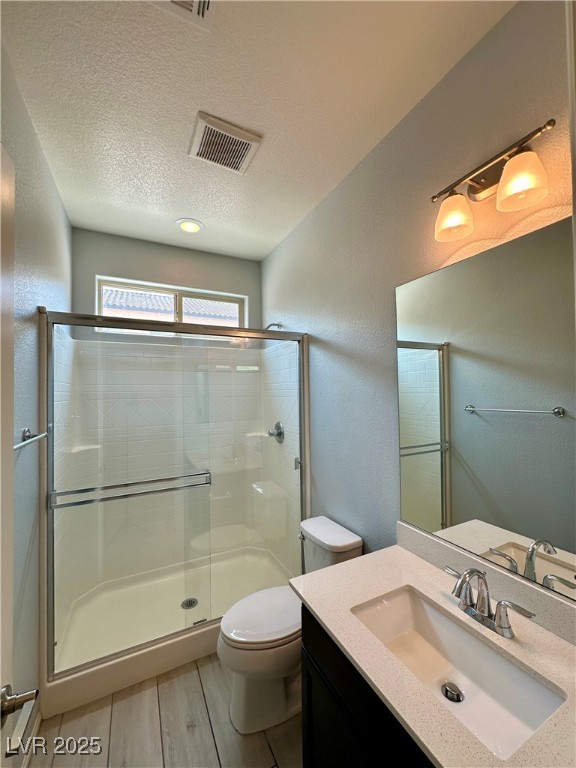 9527 Ridgeglen Court Las Vegas, NV 89148 - Photo 11 of 30 Bathroom featuring a textured ceiling, a textured wall, a shower stall, vanity, and wood finished floors