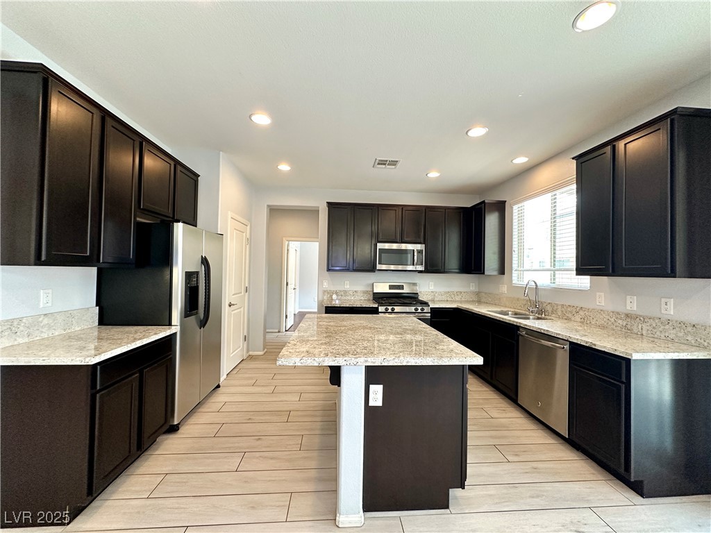 9527 Ridgeglen Court Las Vegas, NV 89148 - Photo 9 of 30 Kitchen featuring a center island, appliances with stainless steel finishes, recessed lighting, wood finish floors, and a kitchen bar
