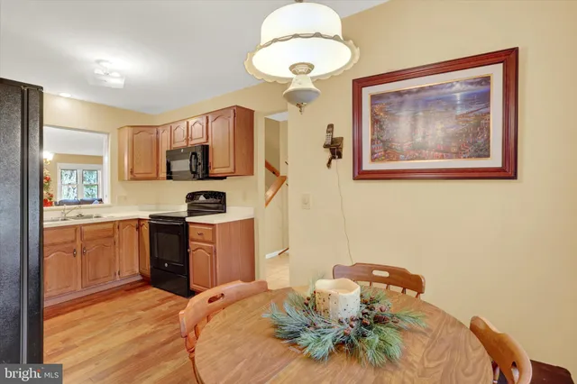 a kitchen with stainless steel appliances granite countertop a refrigerator a stove a sink a microwave a dining table and chairs with wooden floor