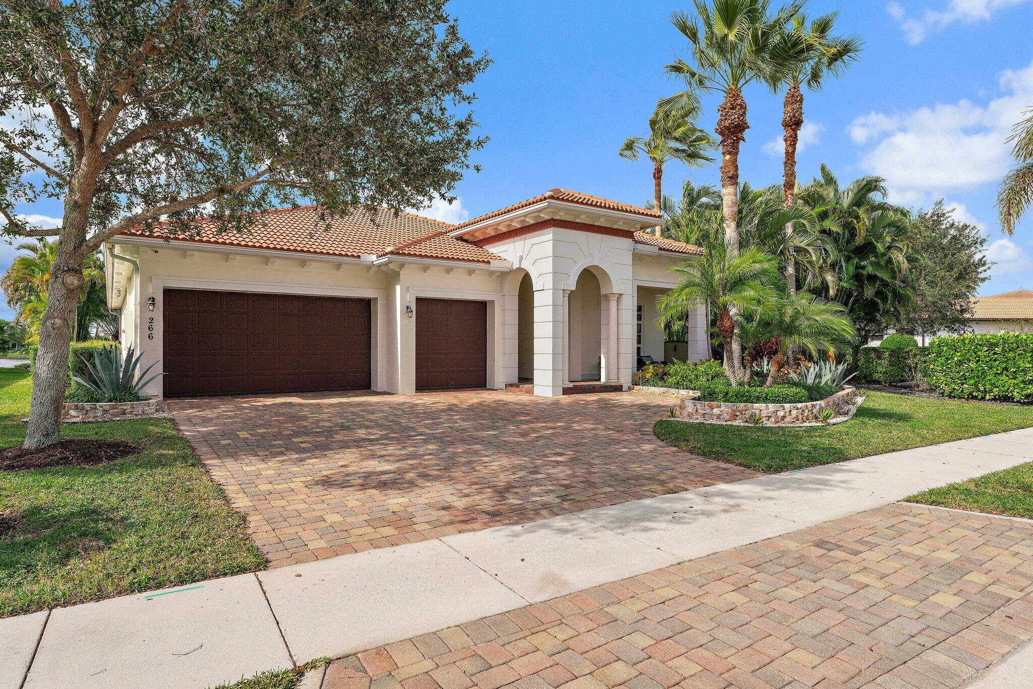 266 Rudder Cay Way Jupiter, FL 33458 - Photo 13 of 79 a front view of a house with a garden and trees