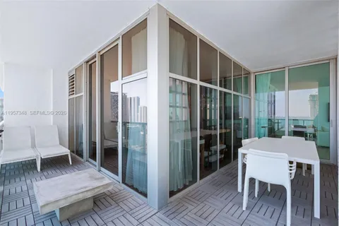 a large living room with stainless steel appliances furniture a large window and a kitchen view
