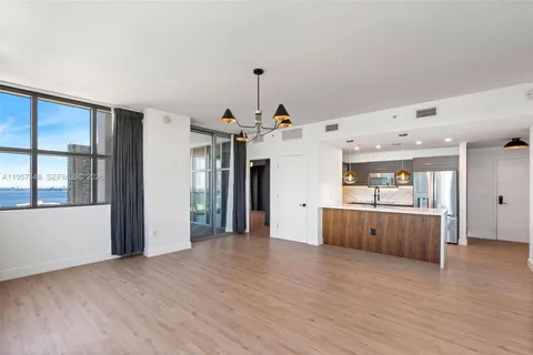 a large kitchen with stainless steel appliances a large counter top a wooden floors and a large window