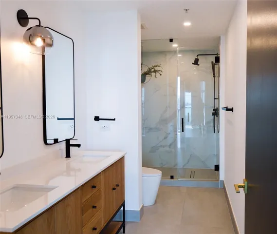 a bathroom with a double vanity sink toilet and shower