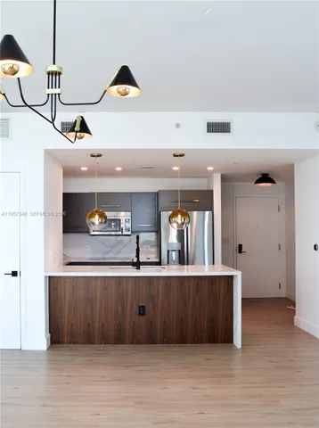 a view of a kitchen with kitchen island a sink stainless steel appliances and cabinets