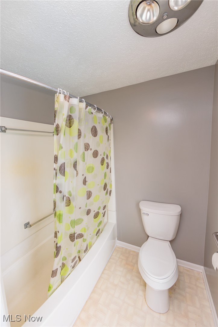 1866 Alpha Road Greenwich, OH 44837 - Photo 32 of 50 Bathroom featuring a textured ceiling, toilet, tile patterned flooring, and shower / bathtub combination with curtain