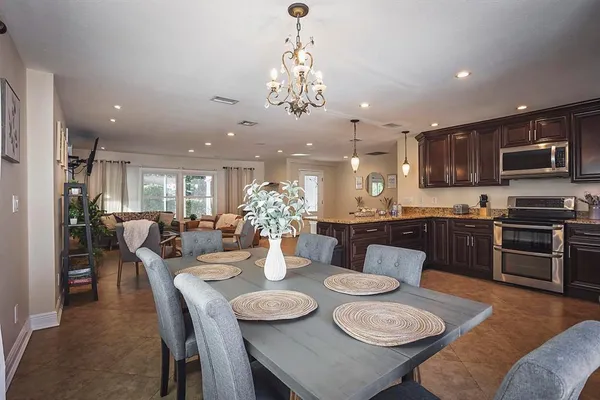 a view of a dining room with furniture a kitchen and chandelier