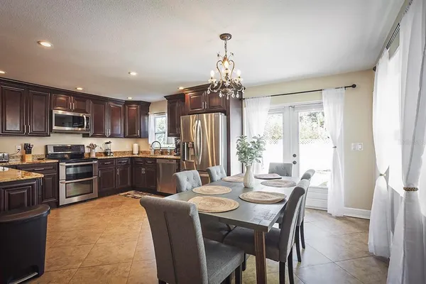 a kitchen with a refrigerator a stove a sink a dining table and chairs