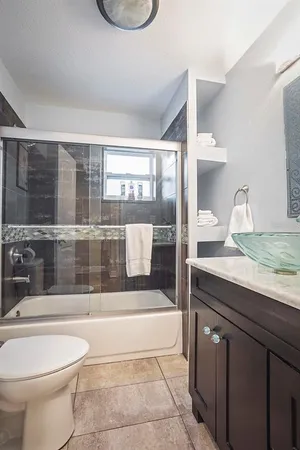 a bathroom with a granite countertop sink a toilet a mirror and bathtub