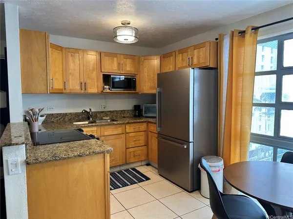 a kitchen with granite countertop a refrigerator a stove a sink a dining table and chairs