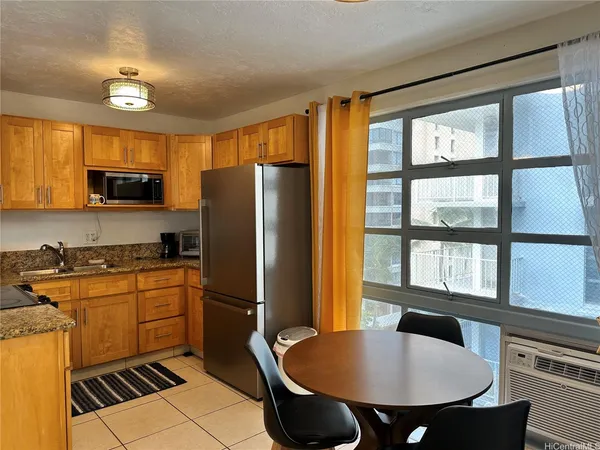 a kitchen with stainless steel appliances granite countertop a stove a refrigerator a kitchen island a sink dishwasher a dining table and chairs with wooden floor