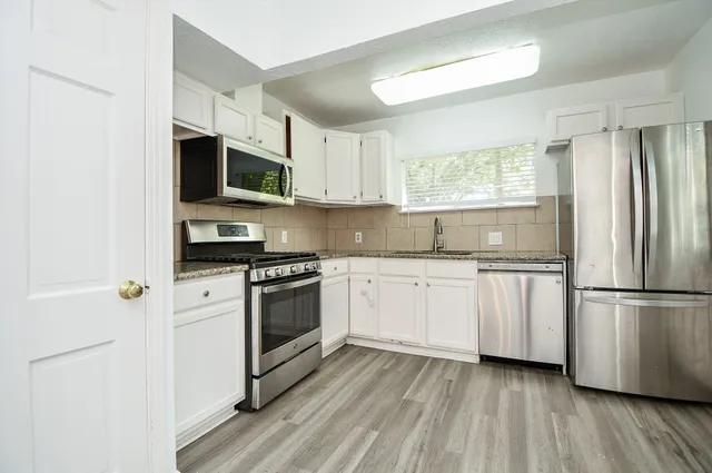 a kitchen with stainless steel appliances granite countertop a refrigerator and a stove top oven