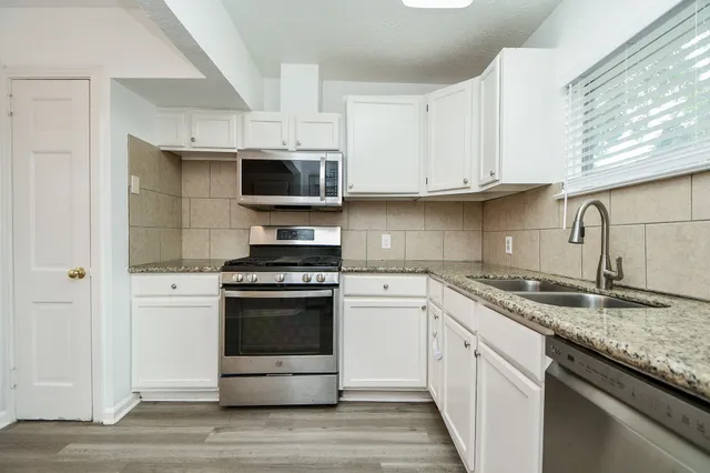 a kitchen with granite countertop a sink dishwasher a stove and a refrigerator