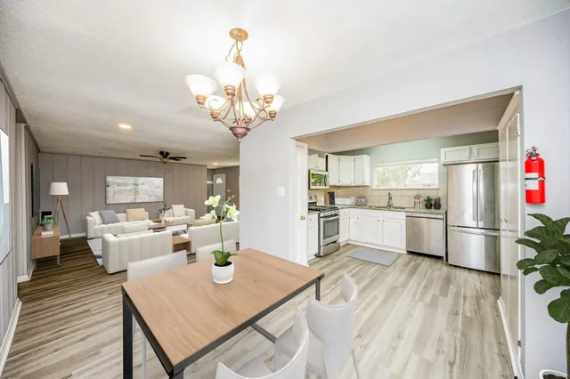 a view of a dining room and livingroom with furniture wooden floor a chandelier