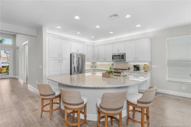 a kitchen with stainless steel appliances granite countertop a stove a sink a dining table and chairs