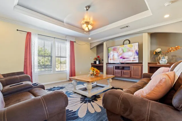 a living room with furniture a chandelier and a flat screen tv
