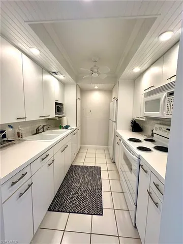 a large white kitchen with a stove a sink and a refrigerator