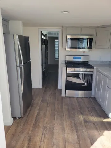 a living room with stainless steel appliances wooden floor and a fireplace