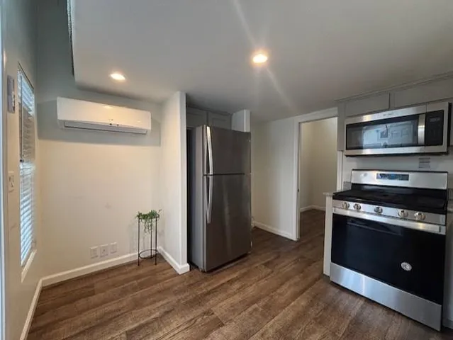 a kitchen with stainless steel appliances granite countertop a refrigerator a sink dishwasher a stove and white countertops with wooden floor