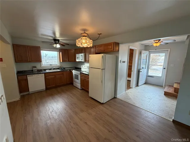 a kitchen with stainless steel appliances granite countertop a refrigerator a sink dishwasher a stove and a dining table with wooden floor