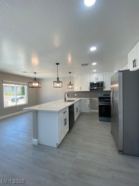 3702 River Canyon Road Las Vegas, NV 89129 - Photo 7 of 35 Kitchen with fridge, white cabinetry, light wood-style flooring, hanging light fixtures, and tasteful backsplash