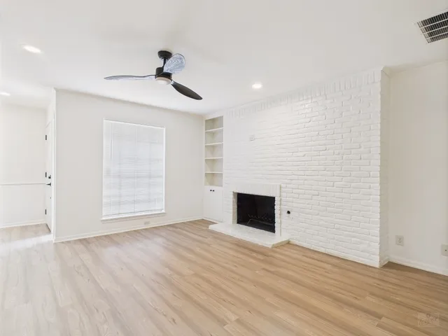 a view of empty room with wooden floor and fireplace