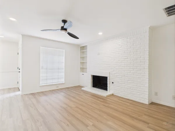 a view of empty room with wooden floor and fireplace
