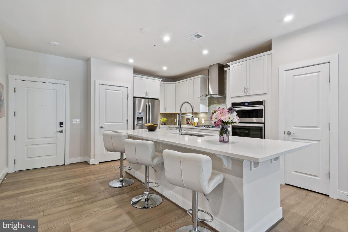 2319 Field Point Road, Unit 107 Herndon, VA 20171 - Photo 4 of 30 a kitchen with stainless steel appliances kitchen island granite countertop a stove a sink a refrigerator white cabinets and wooden floor