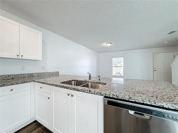 a kitchen with granite countertop a sink and cabinets