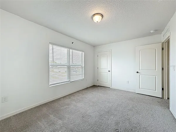 an empty room with a window and a kitchen