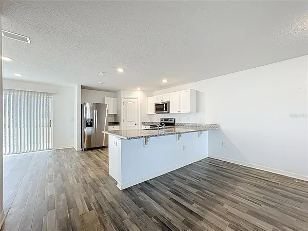 a kitchen with a refrigerator and white cabinets