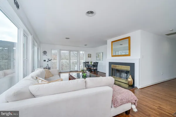 a living room with stainless steel appliances furniture a fireplace and wooden floor