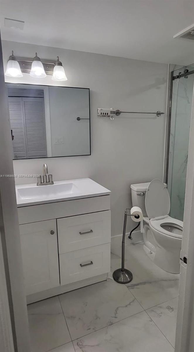5425 Southwest 77th Court, Unit 102D Miami, FL 33155 - Photo 17 of 22 a bathroom with a sink a toilet and a mirror